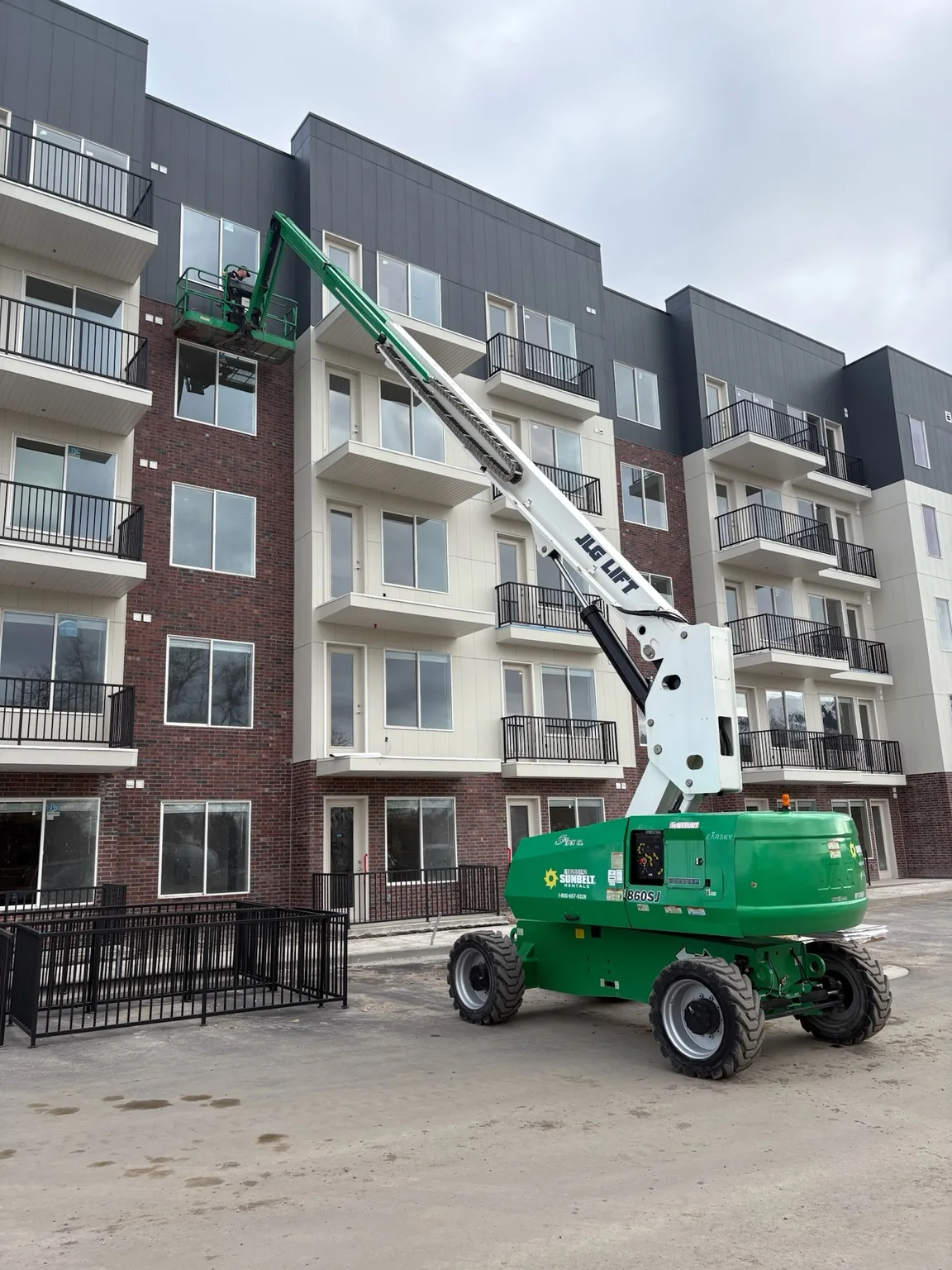 Clearly Clean technician working from a boom lift on a multi-story construction project