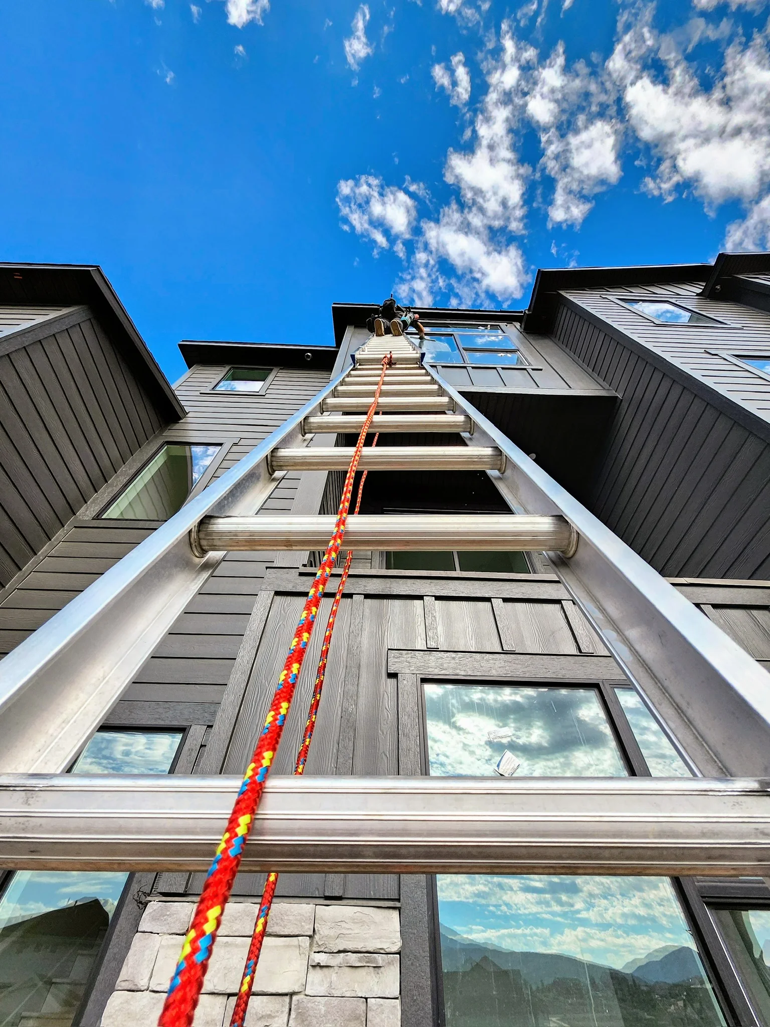 Clearly Clean technician cleaning upper windows from a ladder